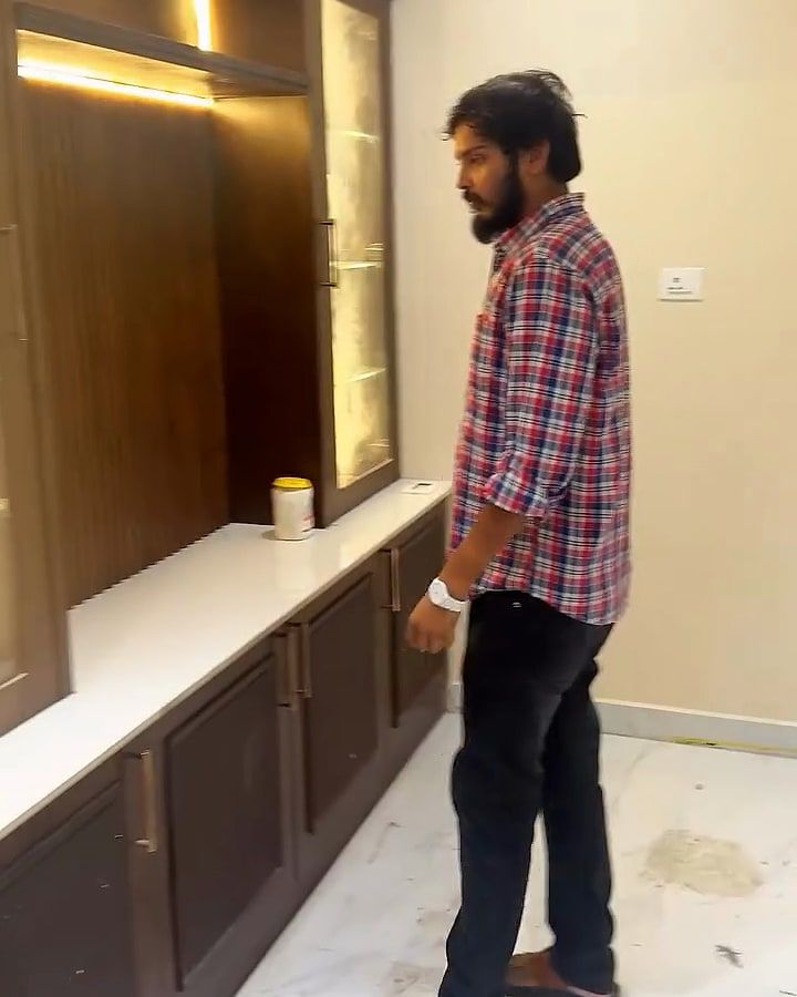 A man stands by a backlit glass display unit over a stone-topped cabinet