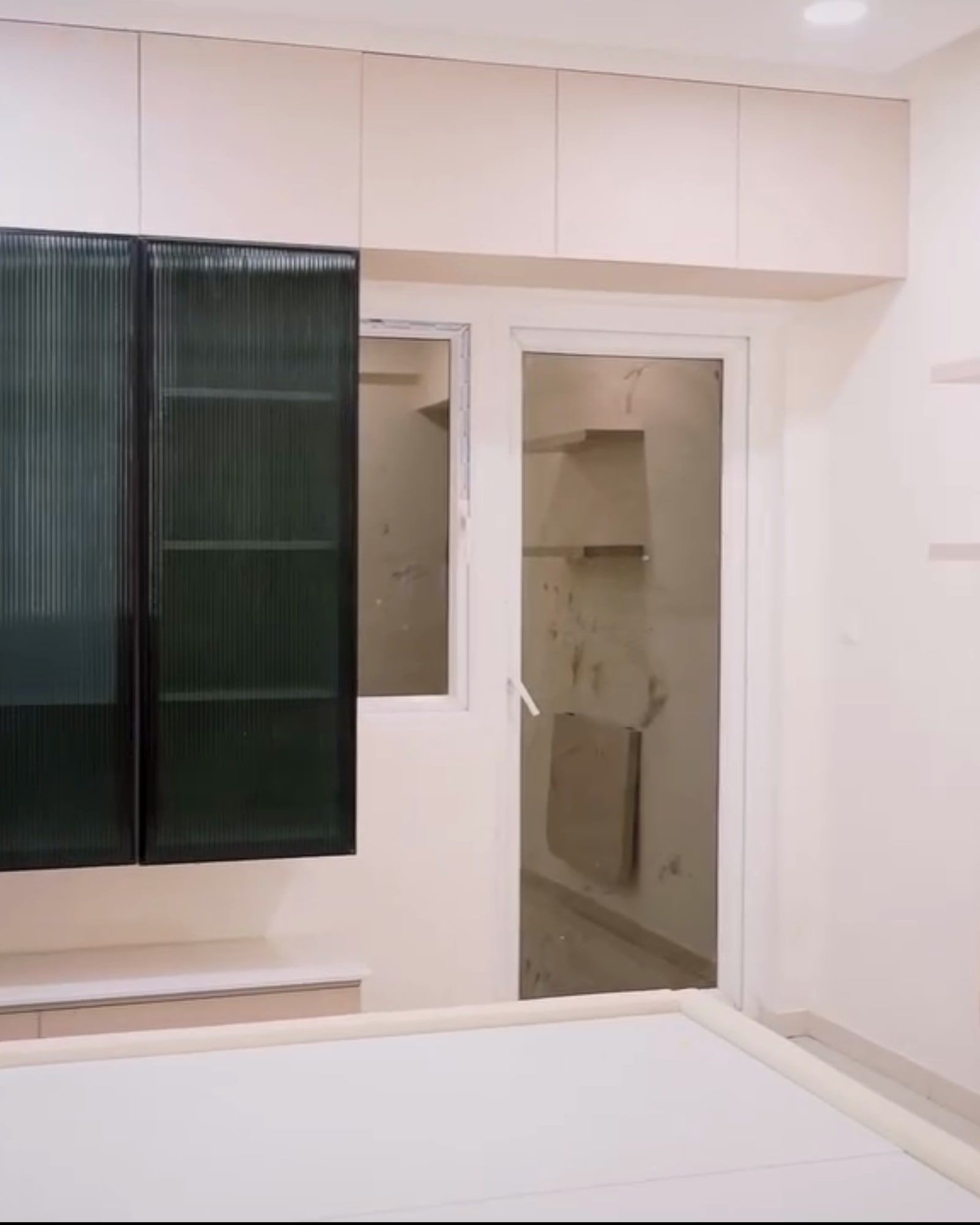Bedroom with tinted green glass wardrobe shutters beside a window