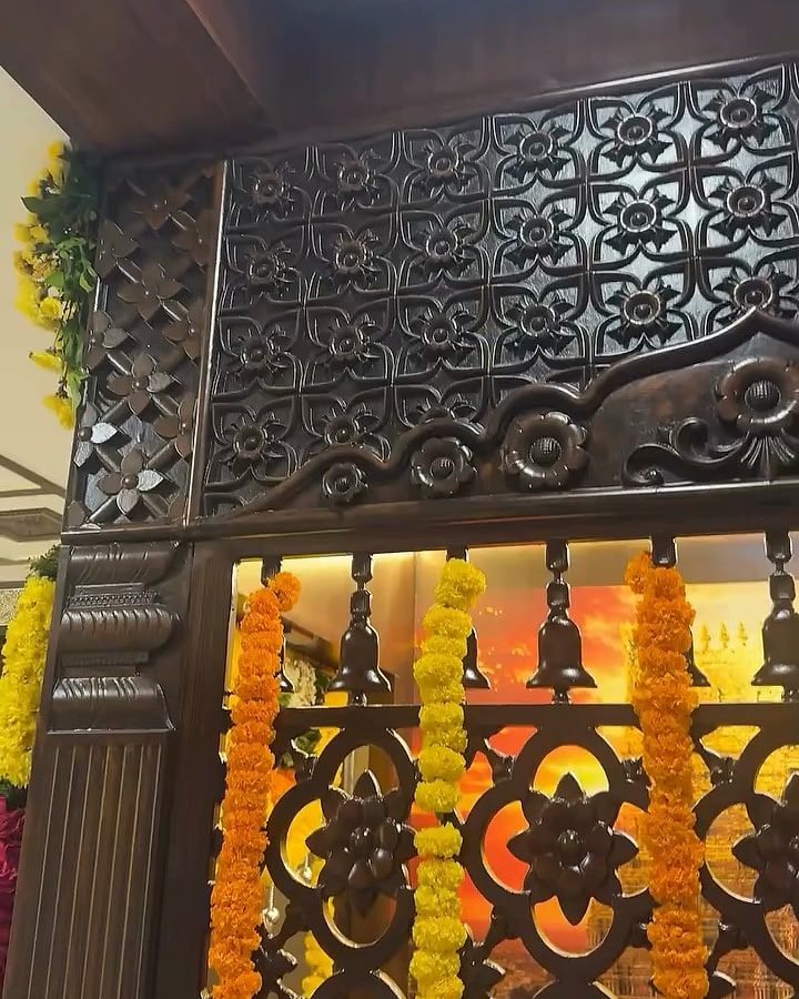 Carved jaali screen strung with marigold garlands, lit from behind