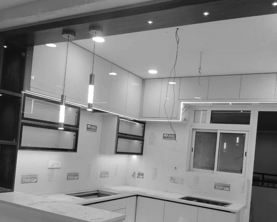 Kitchen with gloss shutters and framed glass uppers, two pendants lit and loose wires for a third