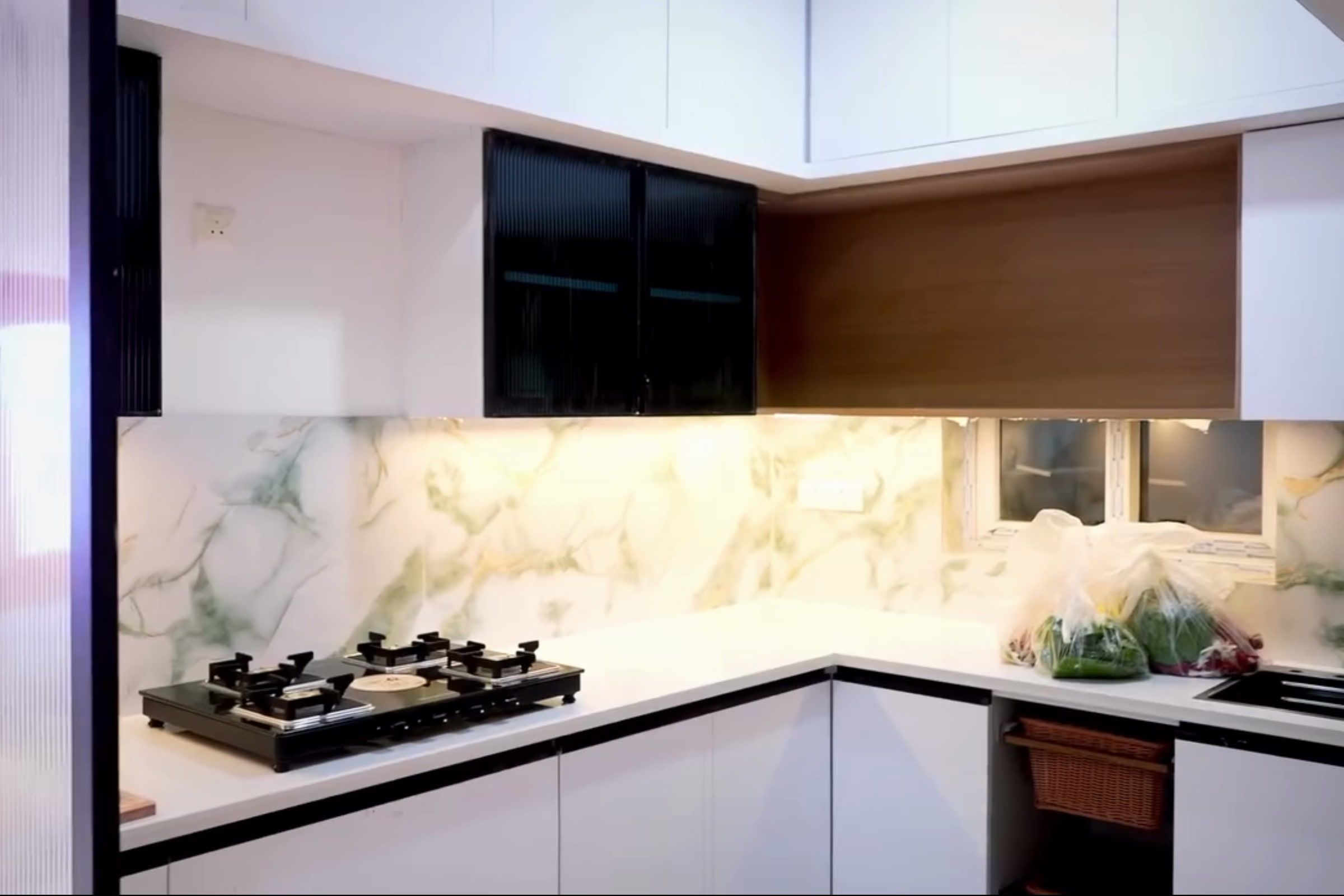L-shaped kitchen with white shutters, black glass uppers, a wood-finish loft and a marble-look backsplash
