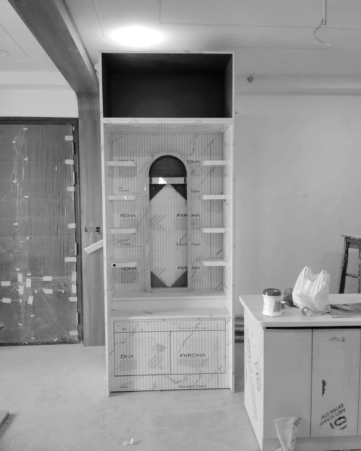Pooja unit under protective film with a paper template of the arch taped in place