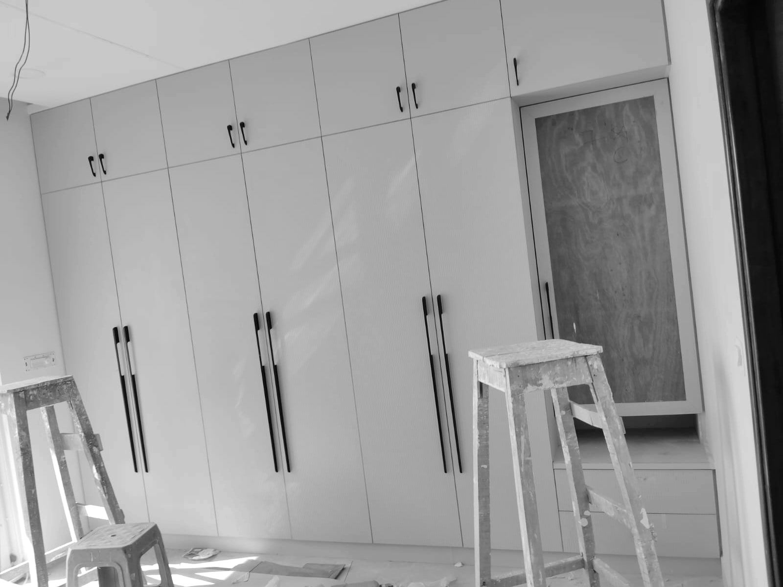 Wardrobe wall with shutters and handles fitted and work stools still in the room