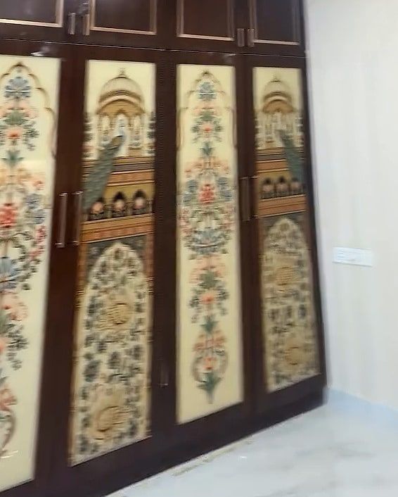Bedroom wall of four walnut-finish wardrobes with floral and peacock art panels, plain loft shutters above