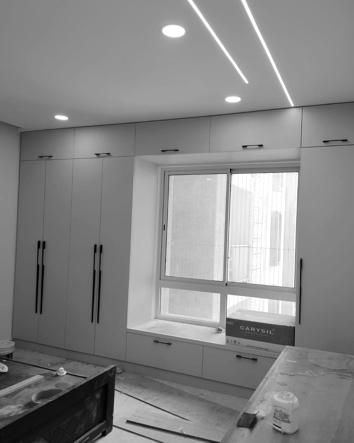 Wardrobes built around a window seat under new linear ceiling lights